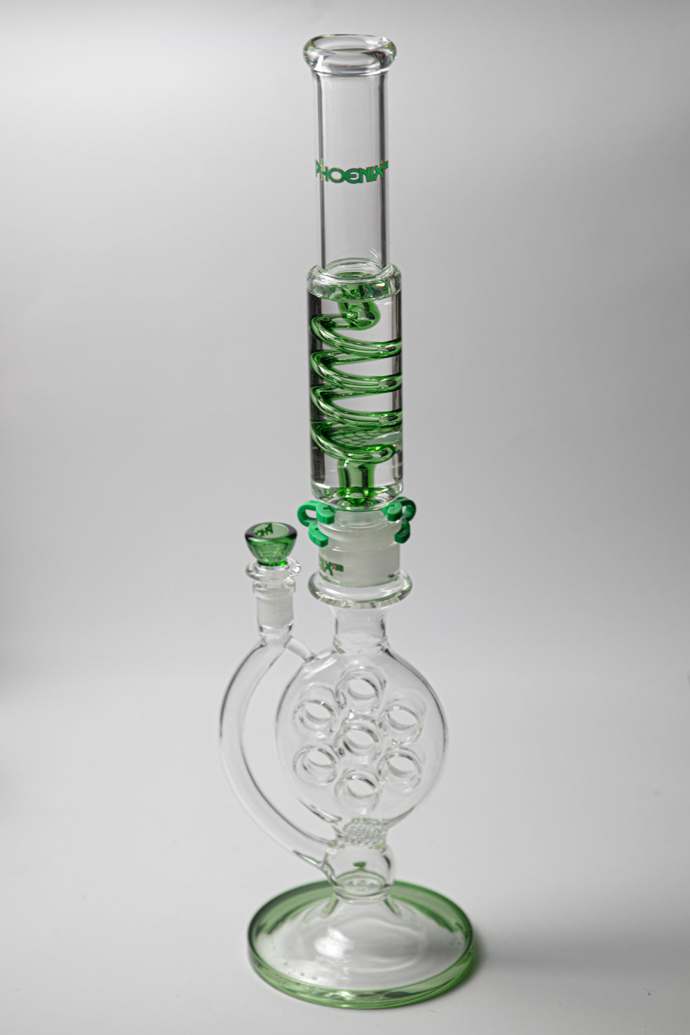 Phoenix Swiss Divided Green Water Pipe – a 21-inch rig for weed and dabs. Now available for sale, this standout piece boasts a striking design, a bowl piece for weed, a bent-down stem, recycler percolator, and a small honeycomb percolator. The incorporated percolators ensure a smooth, cool smoke, preventing water from splashing back . Color green