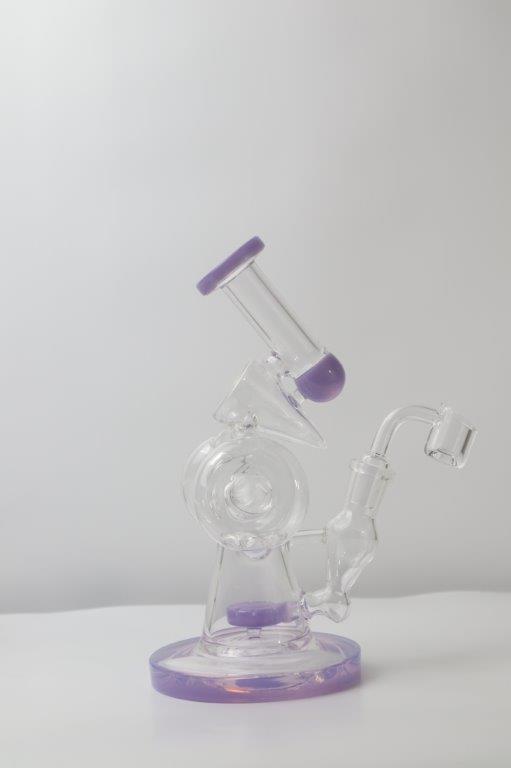 10.5 inch Donut Recycling Rig and Bong, now available in a captivating purple hue – a distinctive shape designed for weed and dabs in water bong style glass. For sale now, this unique piece includes a 14MM male banger/nail and a bent bubbler down stem. The integrated percolator ensures a smooth smoking experience, preventing water splashback, cooling the smoke down, and providing extra filtration, offering both style and functionality with a mesmerizing microscope look