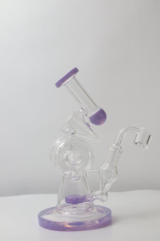10.5 inch Donut Recycling Rig and Bong, now available in a captivating purple hue – a distinctive shape designed for weed and dabs in water bong style glass. For sale now, this unique piece includes a 14MM male banger/nail  and a bent bubbler down stem. The integrated percolator ensures a smooth smoking experience, preventing water splashback, cooling the smoke down, and providing extra filtration, offering both style and functionality with a mesmerizing microscope look
